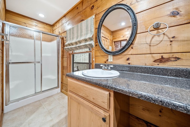 bathroom featuring tile patterned flooring, vanity, a shower with door, and wooden walls