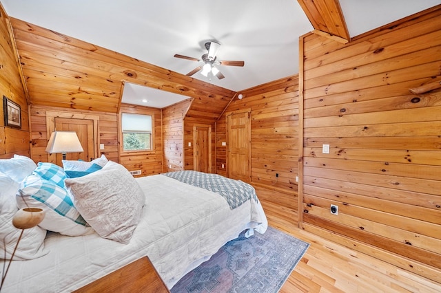 bedroom featuring light wood-type flooring, vaulted ceiling, wooden walls, and ceiling fan