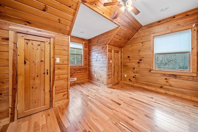 bonus room featuring ceiling fan, vaulted ceiling, wooden walls, and light hardwood / wood-style floors