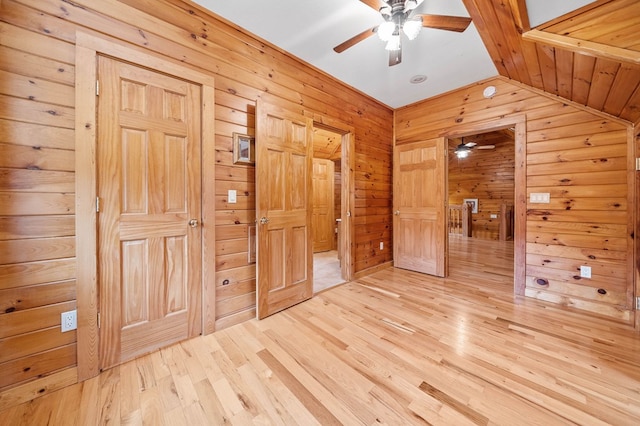 unfurnished bedroom with hardwood / wood-style flooring, vaulted ceiling, and wooden walls