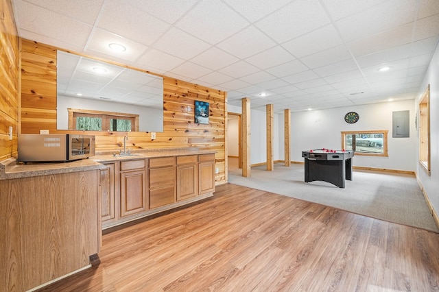 kitchen with light brown cabinetry, electric panel, a drop ceiling, light hardwood / wood-style floors, and sink