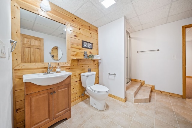 bathroom featuring vanity, a drop ceiling, toilet, and a shower with door