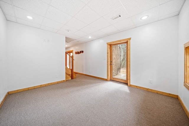 carpeted spare room featuring a drop ceiling