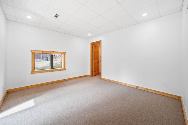 empty room featuring carpet and a drop ceiling