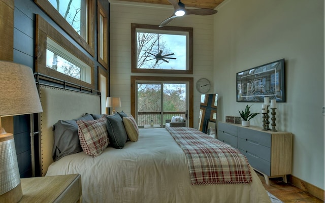 bedroom with a towering ceiling, wood walls, access to exterior, and ceiling fan