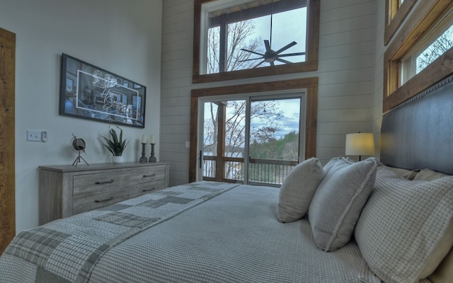 bedroom featuring wood walls, access to exterior, and a towering ceiling