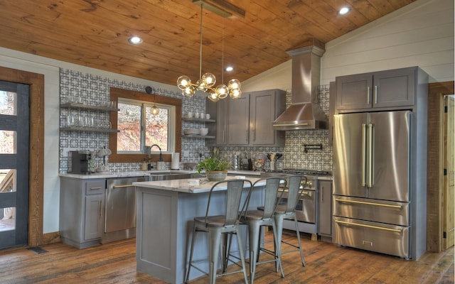 kitchen featuring vaulted ceiling, dark hardwood / wood-style floors, high quality appliances, a center island, and wall chimney range hood