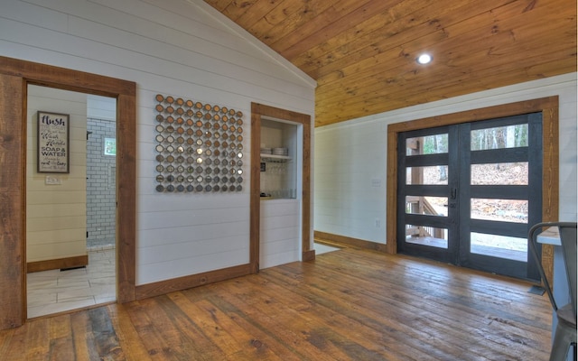 foyer with wooden walls, wood ceiling, wood-type flooring, french doors, and vaulted ceiling