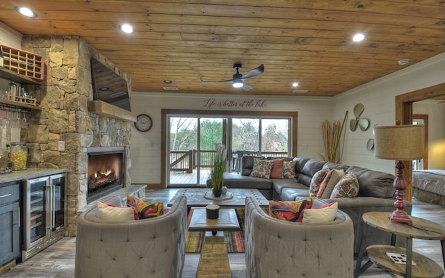 living room featuring a fireplace, wine cooler, wood-type flooring, ceiling fan, and wooden ceiling