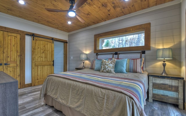 bedroom with a barn door, ceiling fan, hardwood / wood-style flooring, and wood ceiling