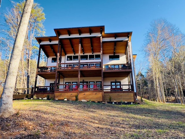 rear view of house with a lawn and a wooden deck