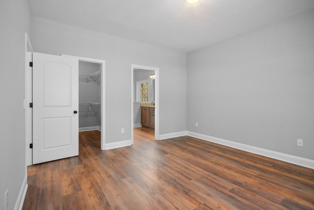 unfurnished bedroom with dark hardwood / wood-style flooring, a walk in closet, and a closet