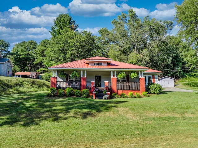 view of front of house with a front yard, covered porch, an outdoor structure, brick siding, and metal roof