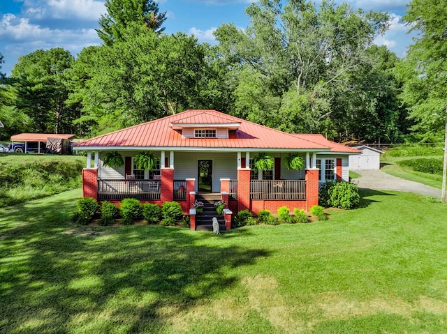 view of front of house with an outbuilding, a standing seam roof, metal roof, a front lawn, and covered porch