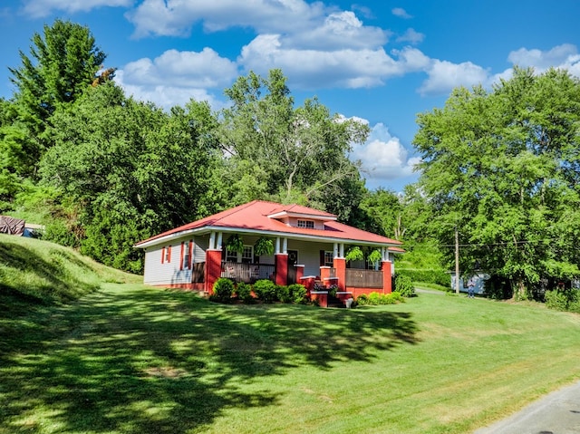 view of front of house featuring covered porch, a front lawn, and metal roof