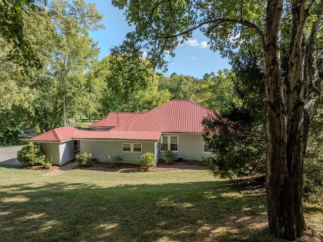 rear view of property with metal roof and a yard