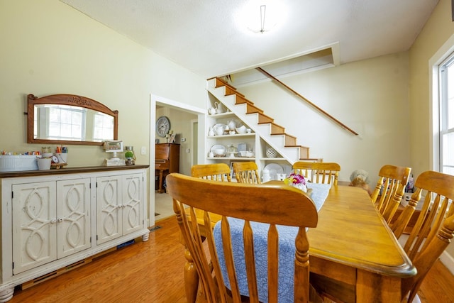 dining area with built in features, stairway, and light wood finished floors