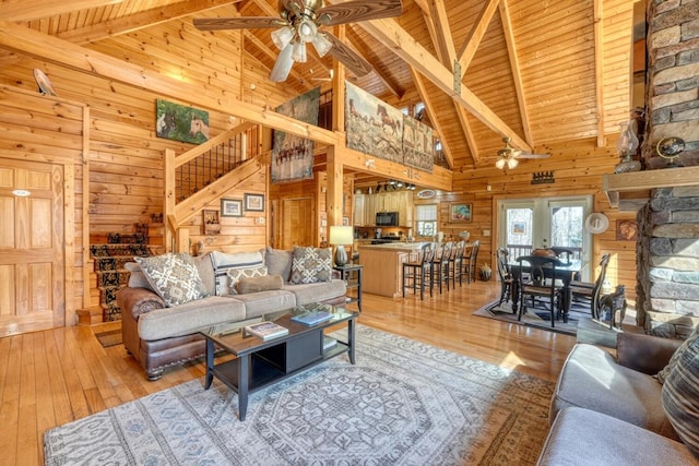 living room with light wood-type flooring, wooden walls, wooden ceiling, and ceiling fan