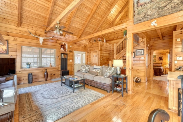 living room with light hardwood / wood-style floors, wooden walls, wooden ceiling, and beamed ceiling