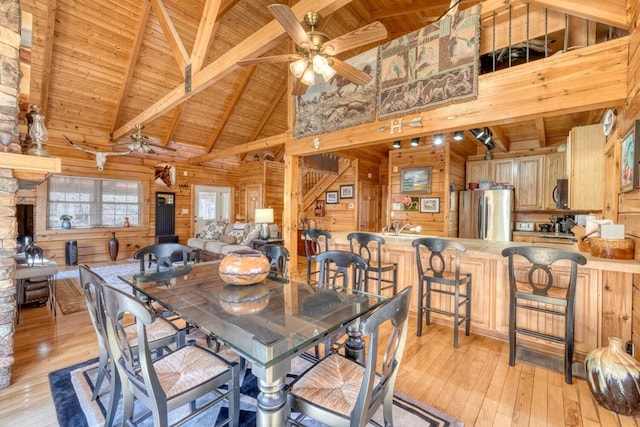 dining room featuring light hardwood / wood-style floors, wood ceiling, beamed ceiling, and wood walls