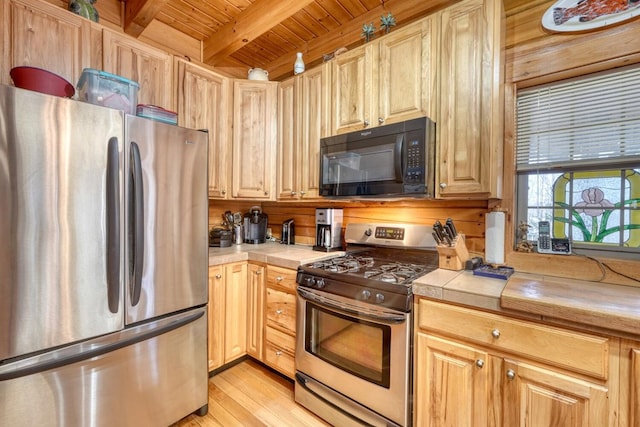 kitchen with tile countertops, stainless steel appliances, light hardwood / wood-style floors, wood ceiling, and beamed ceiling