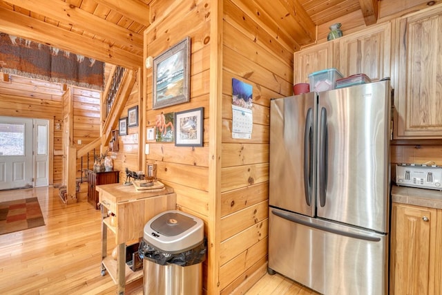 kitchen featuring light brown cabinetry, wooden walls, light hardwood / wood-style floors, stainless steel refrigerator, and wooden ceiling