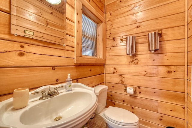 bathroom featuring sink, wood walls, and toilet