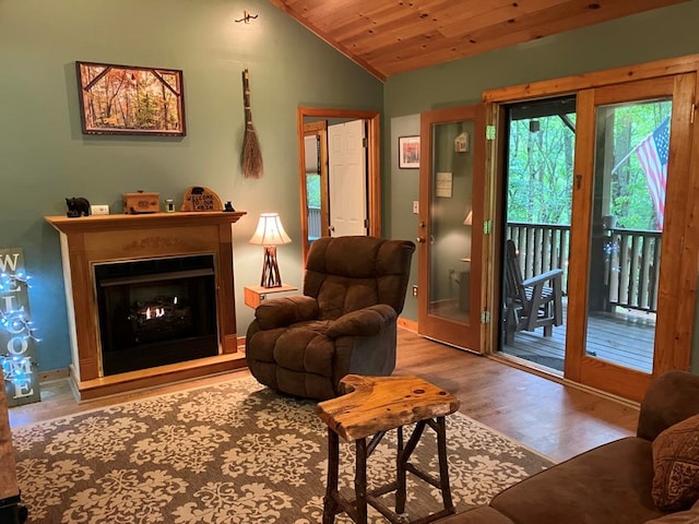living area with wood finished floors, a warm lit fireplace, lofted ceiling, and wooden ceiling