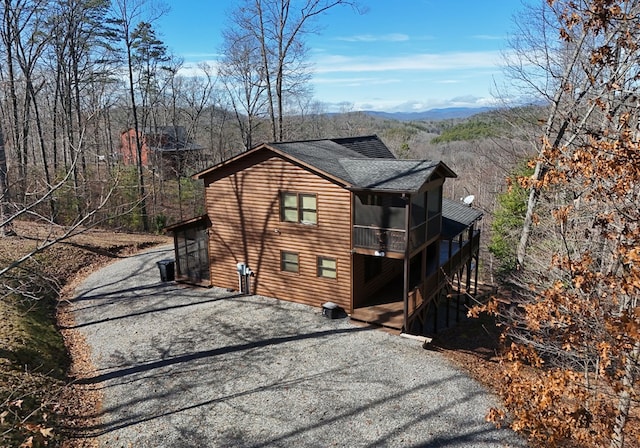 view of side of home featuring aphalt driveway, a mountain view, a shingled roof, stairway, and log veneer siding