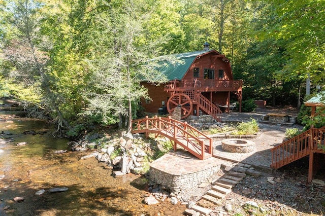 rear view of property with a deck with water view and an outdoor fire pit