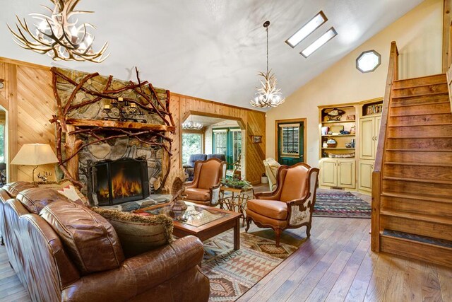 living room with an inviting chandelier, wooden walls, a fireplace, and hardwood / wood-style floors