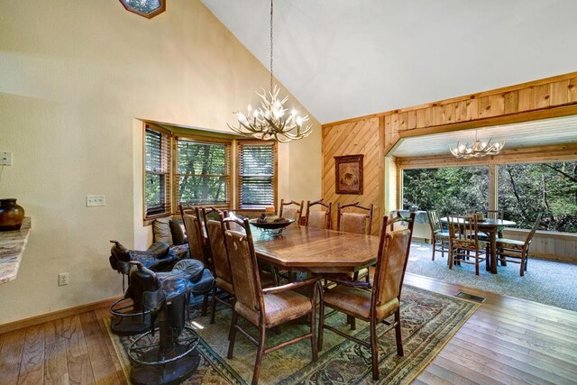 dining area with wooden walls, a chandelier, and a healthy amount of sunlight