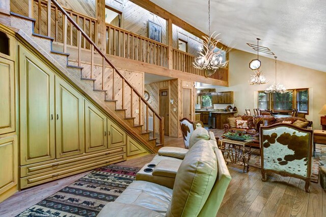 living room featuring an inviting chandelier, high vaulted ceiling, and hardwood / wood-style flooring