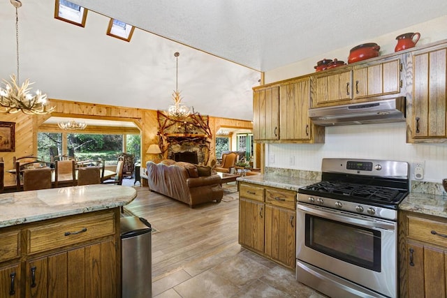 kitchen with pendant lighting, stainless steel gas stove, wood walls, and a chandelier