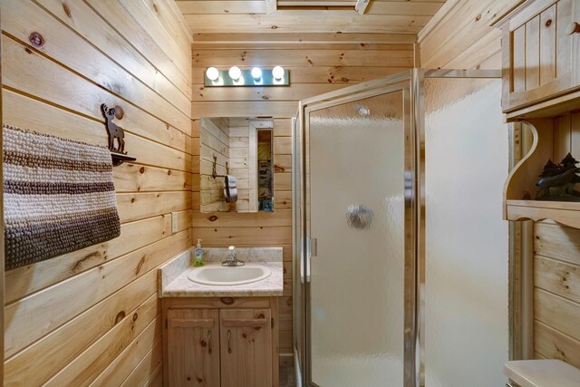 bathroom featuring wood walls, vanity, wooden ceiling, a shower with door, and toilet