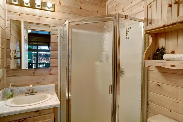 bathroom featuring vanity, wooden walls, a shower with shower door, and toilet