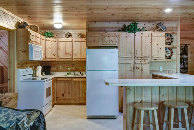 kitchen with kitchen peninsula, wooden walls, white appliances, light brown cabinetry, and wooden ceiling