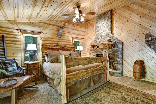 carpeted bedroom with ceiling fan, wooden walls, high vaulted ceiling, wooden ceiling, and a fireplace