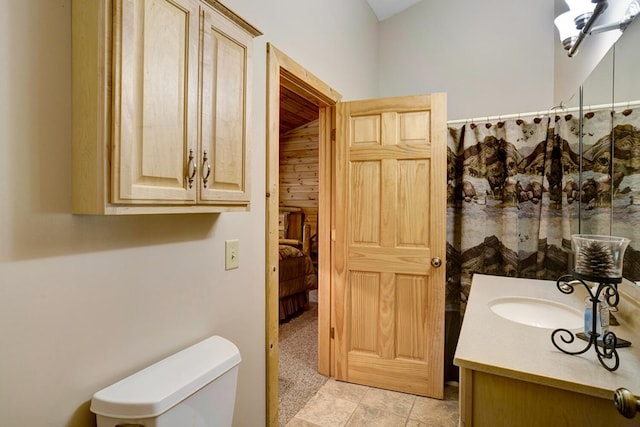 bathroom featuring wood walls, vanity, and toilet