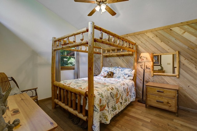 bedroom with wood walls, dark hardwood / wood-style floors, ceiling fan, and vaulted ceiling