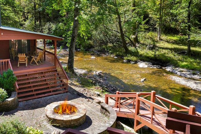 view of yard featuring an outdoor fire pit and a deck with water view