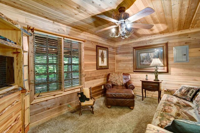 living area featuring ceiling fan, wooden walls, and carpet flooring