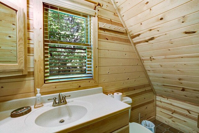 bathroom with vanity, wooden walls, and vaulted ceiling