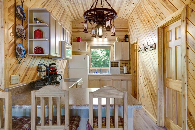 kitchen with white appliances, wooden walls, lofted ceiling, and light brown cabinets