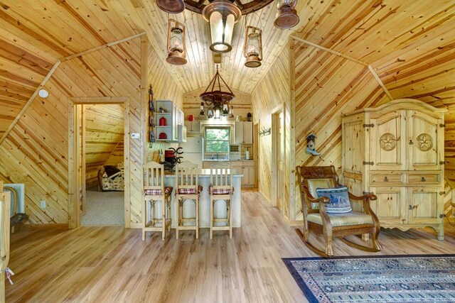 sitting room with light hardwood / wood-style flooring, wooden walls, and wooden ceiling