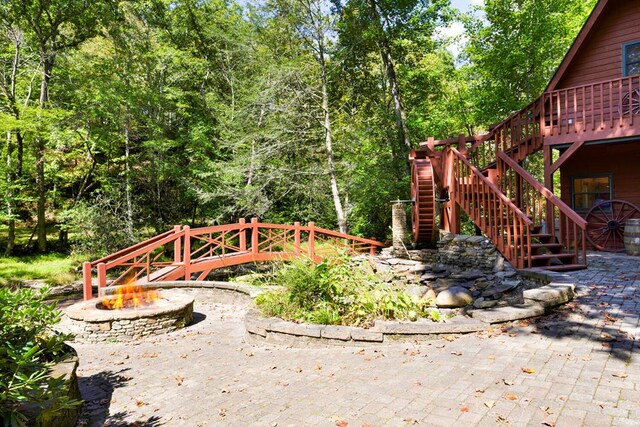 view of yard featuring a fire pit, a deck, and a patio area