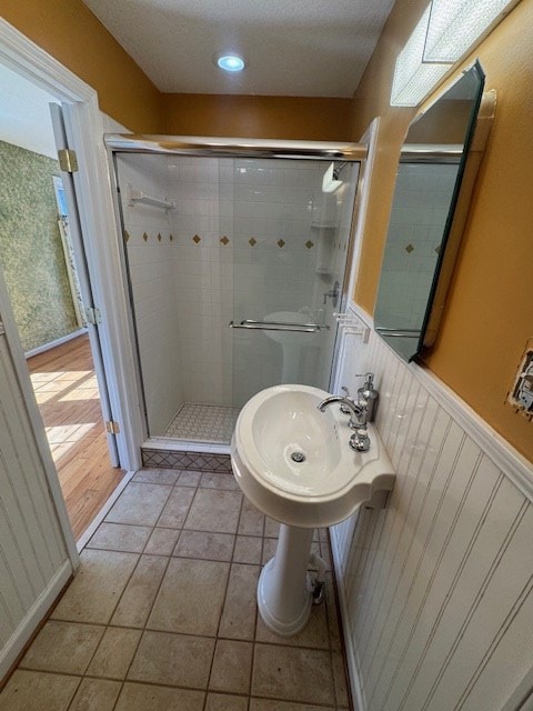 full bath featuring a wainscoted wall, a stall shower, and tile patterned flooring