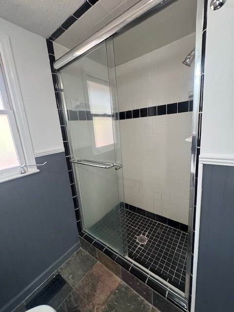 full bath with a textured ceiling and a shower stall