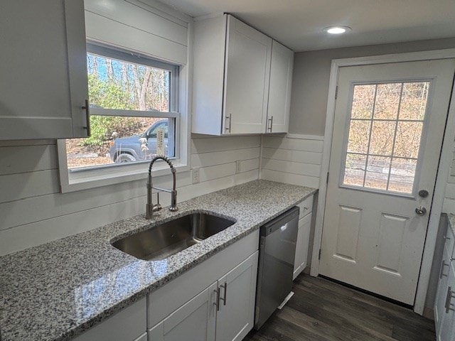 kitchen featuring tasteful backsplash, stainless steel dishwasher, dark wood-style floors, white cabinetry, and a sink