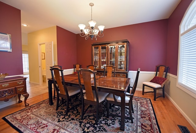 dining space with a healthy amount of sunlight, light wood-type flooring, and an inviting chandelier